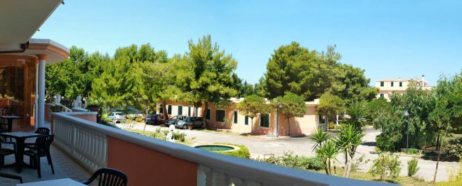Balcone con sedie, vista giardino e alberi.