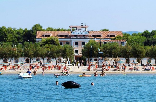 Spiaggia affollata davanti a un grande hotel.