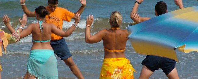 Persone in spiaggia partecipano a una lezione di danza.
