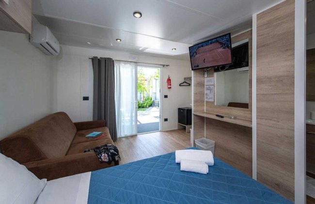 Stanza con letto blu, divano marrone e TV.