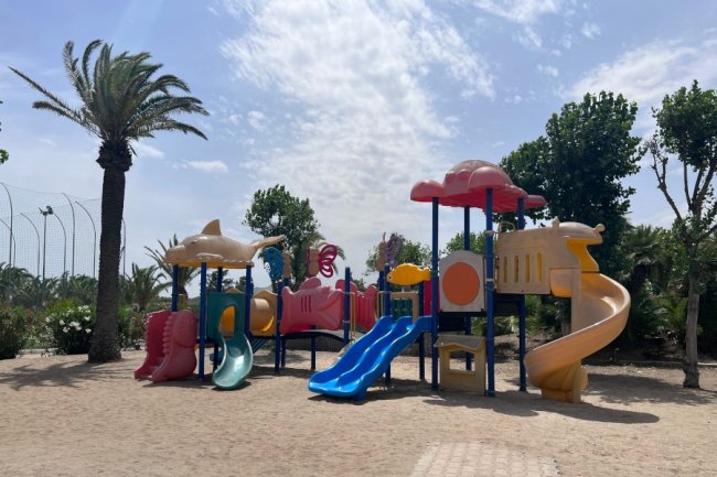 Parco giochi con scivoli colorati su sabbia.