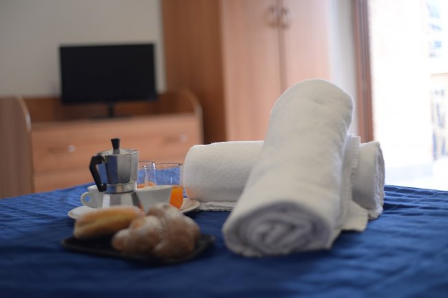 Colazione con caffettiera e dolci su un tavolo blu.