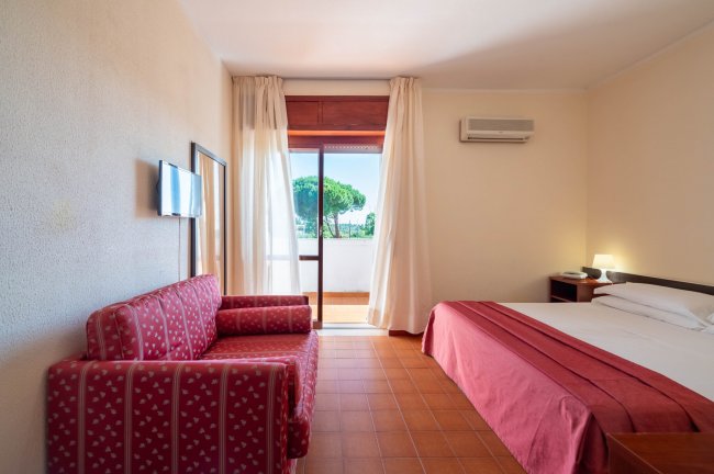 Camera con divano rosso, letto, TV e balcone.