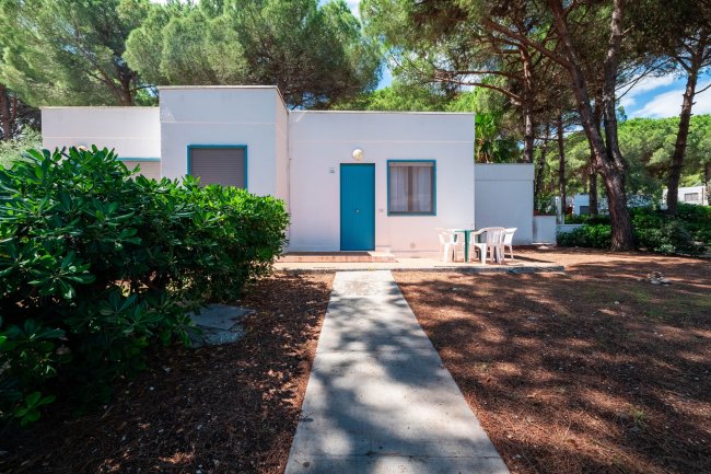 Casa bianca con porta blu tra gli alberi.