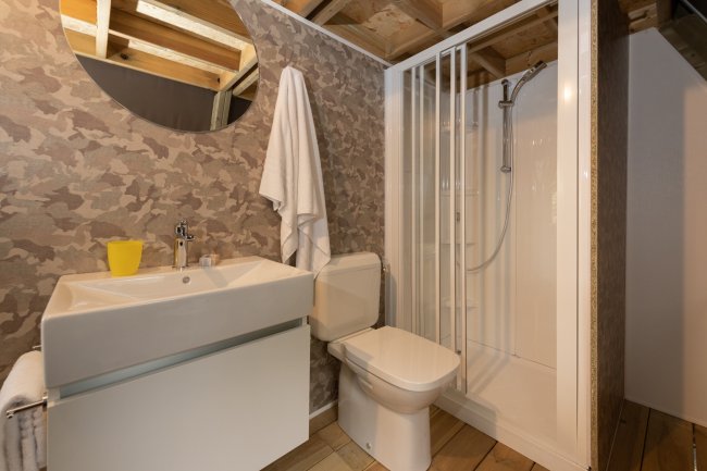 Bagno moderno con doccia, lavandino e specchio rotondo.