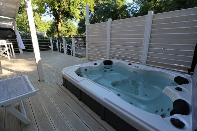 Vasca idromassaggio su terrazza con pavimento in legno.