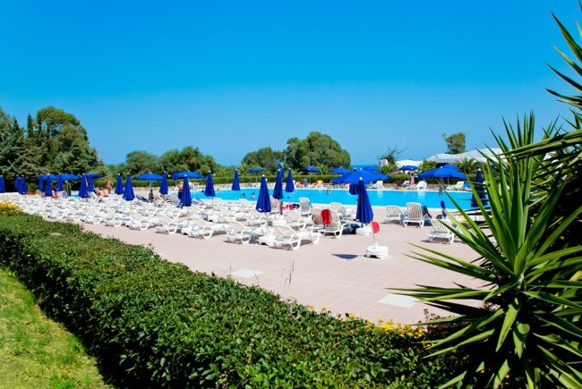 Piscina con lettini bianchi e ombrelloni blu.