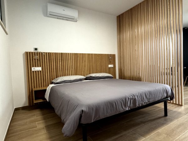 Camera minimalista con letto matrimoniale e parete in legno.