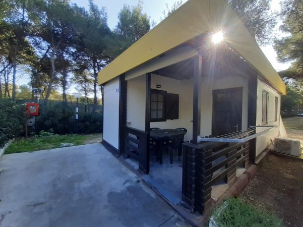 Bungalow in campagna con tavolo e sedie sotto il portico.