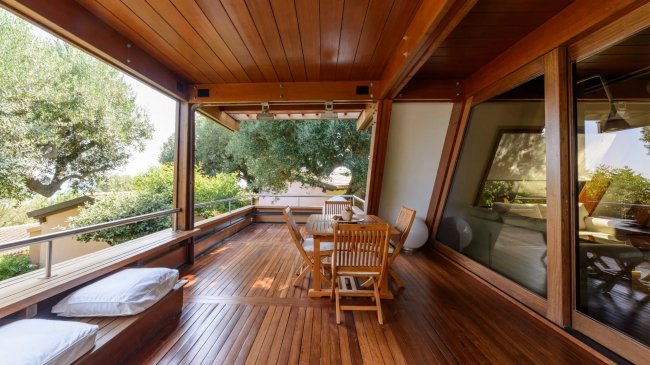 Veranda in legno con tavolo e sedie.