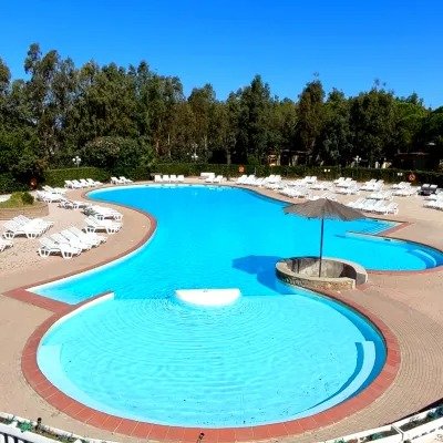 Piscina con lettini e ombrelloni, cielo azzurro.