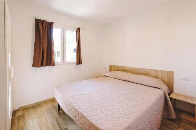 Camera con letto matrimoniale e tende marroni.