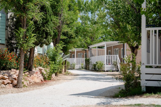 Stradina con case mobili e vegetazione.