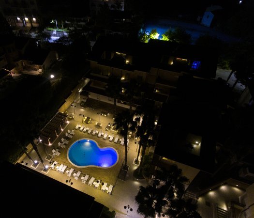 Piscina illuminata di notte circondata da lettini.