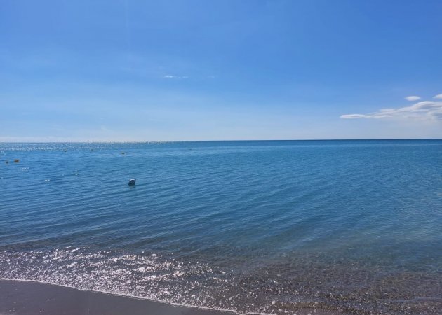 Spiaggia con mare calmo e cielo sereno.