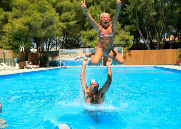 Persona lancia in aria una bambina in una piscina.