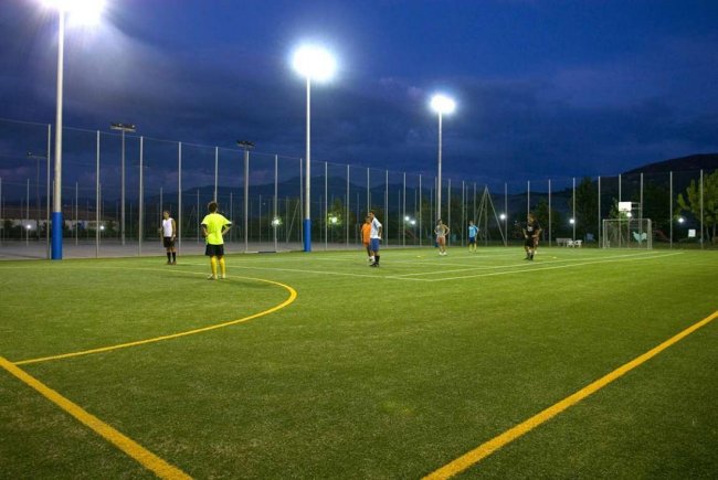 Un campo da calcio illuminato di notte con giocatori sul terreno di gioco.