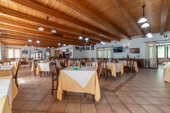 Una sala ristorante spaziosa con tavoli apparecchiati e soffitto in legno.