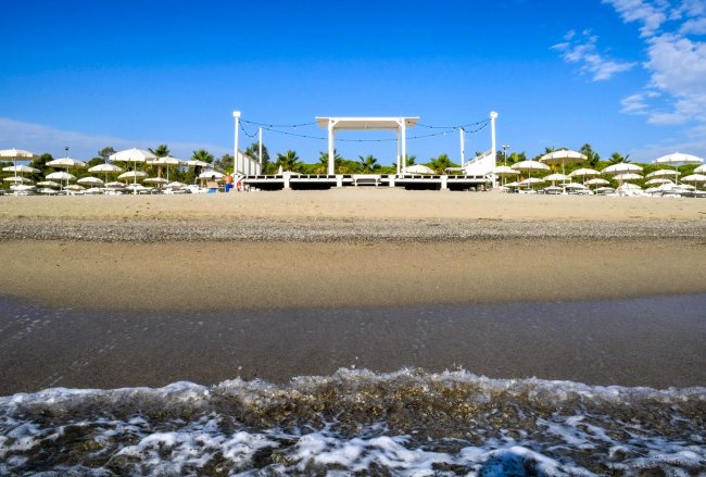 Una spiaggia con pedana bianca e ombrelloni.