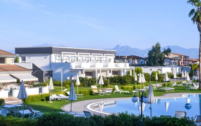 Resort con piscine, ombrelloni e montagne sullo sfondo.