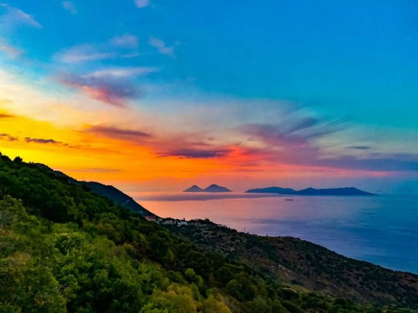 Tramonto sul mare con isole in lontananza. Verde collina sulla sinistra.