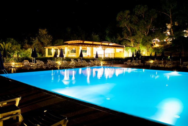 Grande piscina illuminata di fronte a un edificio.