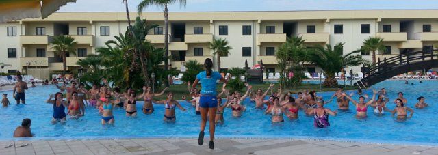 Hotel con piscina piena di persone che seguono un istruttore.