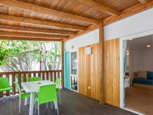 Terrazzino in legno con tavolo e sedie verdi.