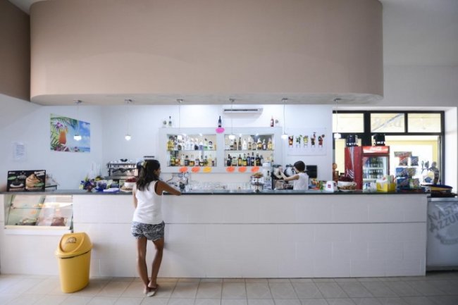 Interno di un bar con una persona che ordina al bancone bianco.