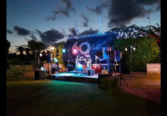 Palco all'aperto con strumenti musicali e luci colorate.