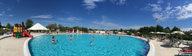 Piscina all'aperto con scivolo e ombrelloni.